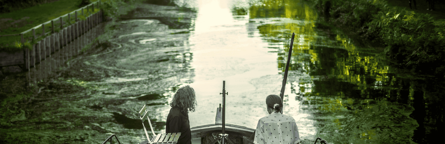 Photo de deux artistes de dos sur une péniche.