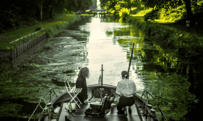 Photo de deux artistes de dos sur une péniche.