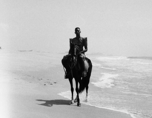Photo en noir et blanc. Personne à cheval au bord de plage.