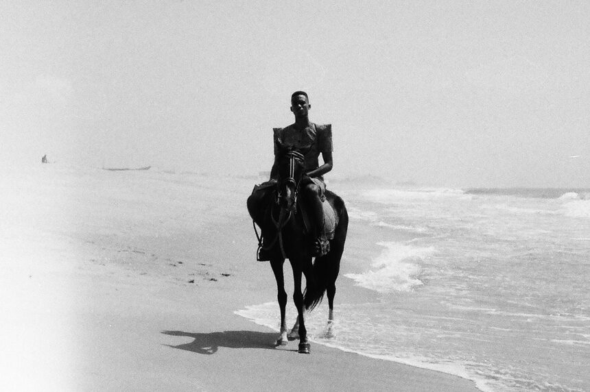 Photo en noir et blanc. Personne à cheval au bord de plage.