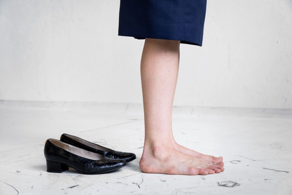 Focus sur les jambes de la danseuse avec ses chaussures derrière elle.