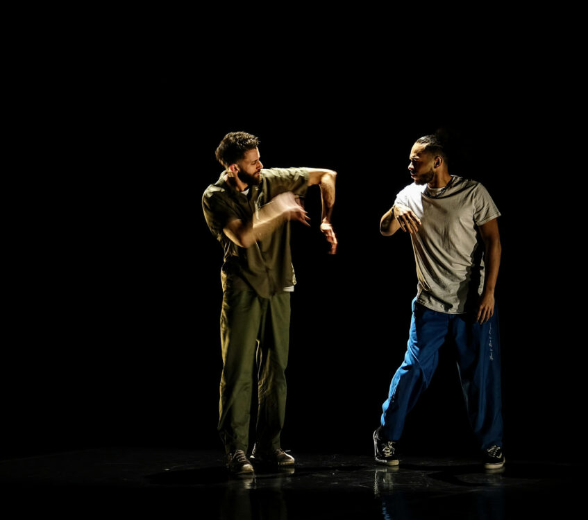 Deux danseurs en mouvement avec fond noir au spectacle Dans l'arène.