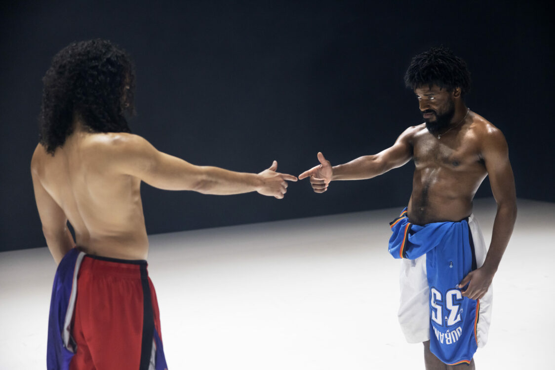 Deux danseurs qui se font face en se pointant du doigt, comme le geste d'une arme.