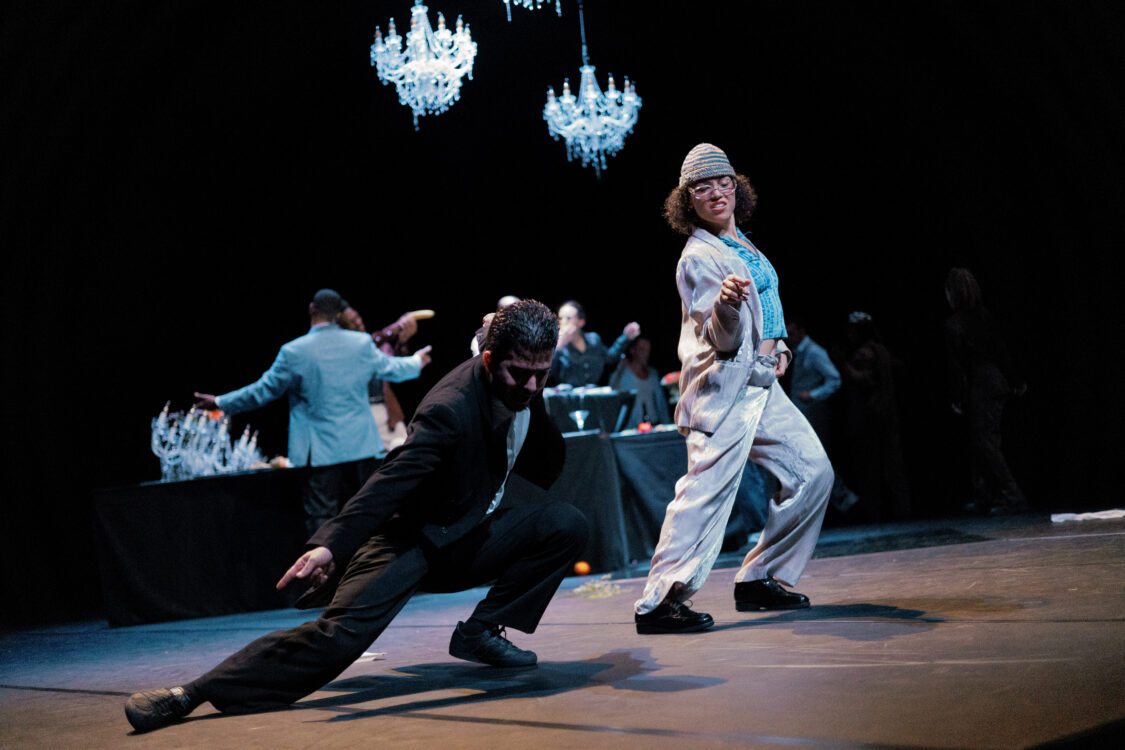 Deux danseurs en mouvement en premier plan, les autres danseurs à l'arrière.