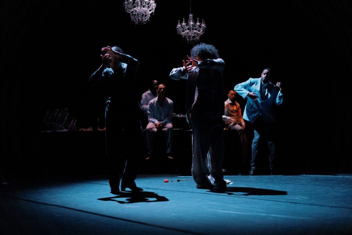 Deux danseurs en mouvement en premier plan, les autres danseurs à l'arrière.