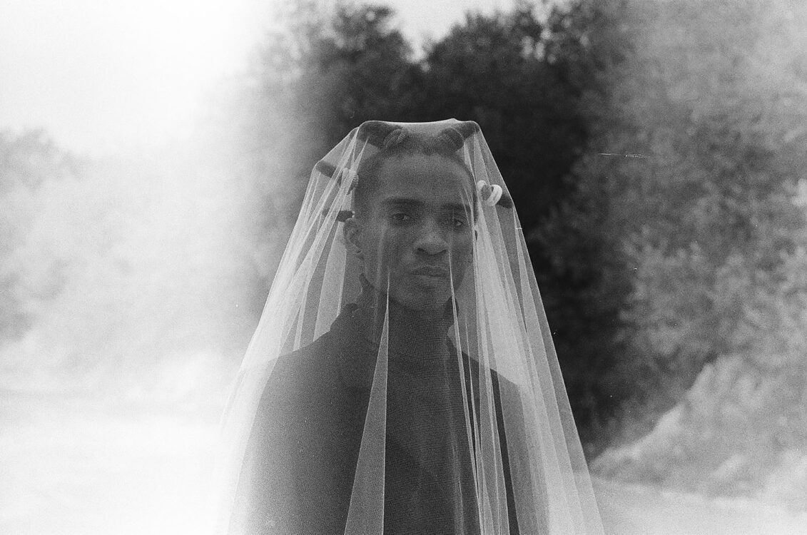 Photo en noir et blanc. Portrait d'une personne sous un voile transparent.