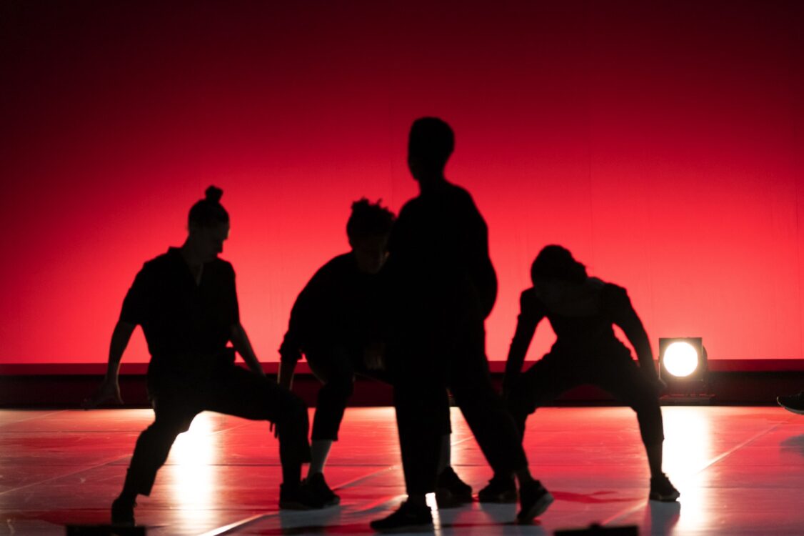 Danseuses dans l'ombre avec un fond rouge.
