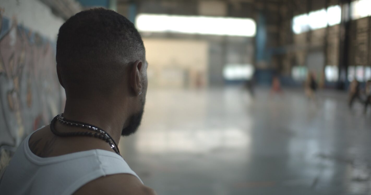 Premier plan rapproché sur un homme de dos faisant face à une salle de danse.