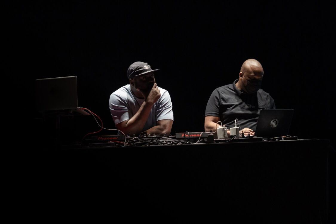 Photo de deux artistes, fond noir.