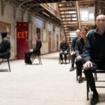 Des personnes assises sur des chaises à plus ou moins longue distance de la caméra.