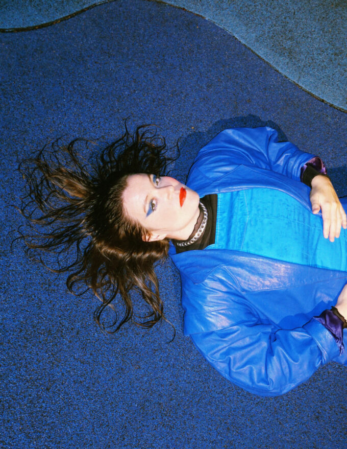 Photo d'une artiste allongée au sol, vêtue de bleue.